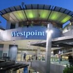 Exterior view of the illuminated Westpoint shopping center entrance at dusk.