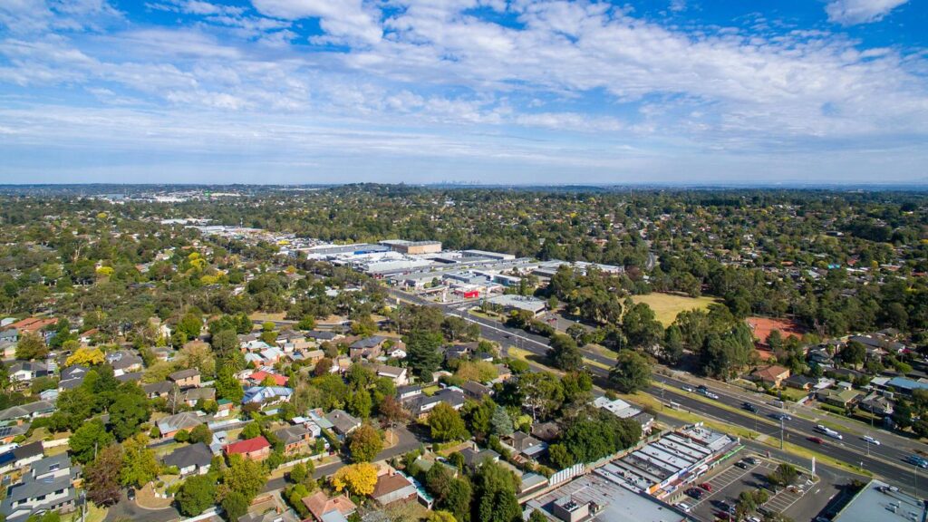 An aerial view of a sprawling suburban neighbourhood featuring residential homes with red and grey roofs