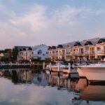 A view of a quiet marina at twilight with luxury motorboats moored in the foreground
