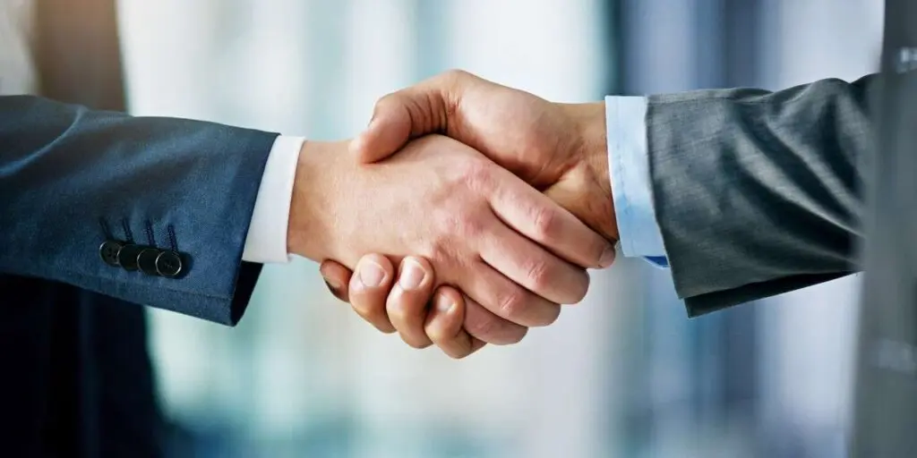 A close-up shot of two people in business suits shaking hands.