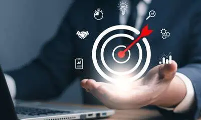 A conceptual image of a person in a business suit sitting at a laptop, with their hand held out toward a glowing digital target icon.