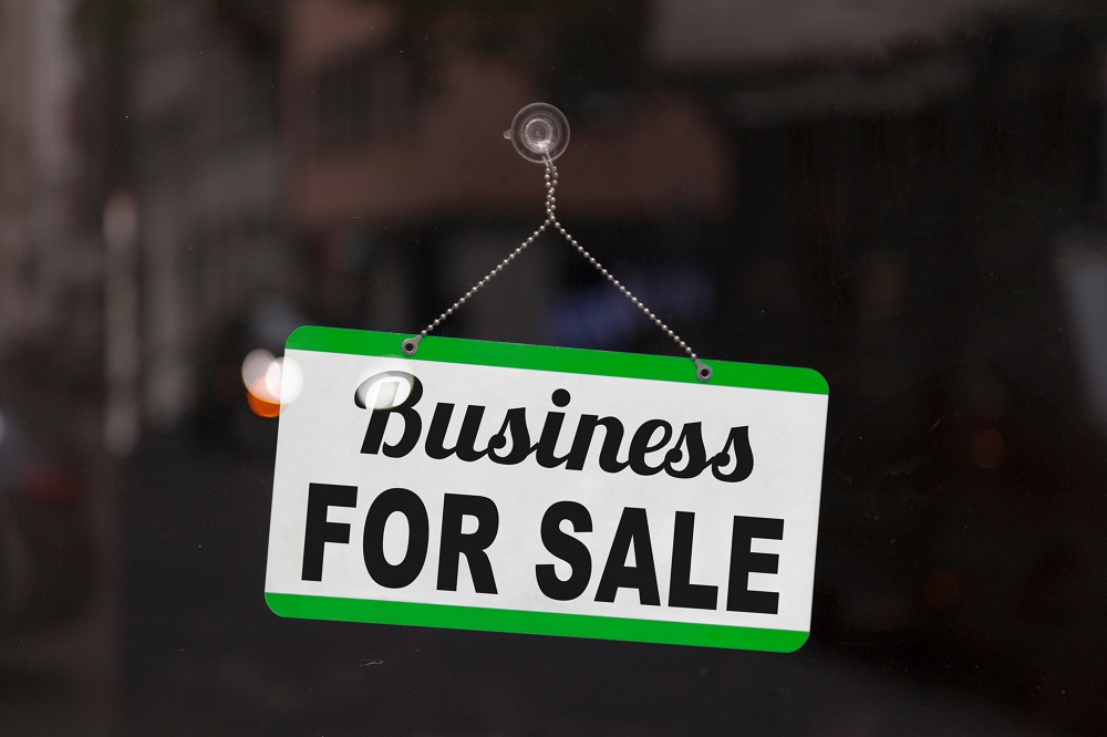 A white rectangular sign with a green border and the words "Business FOR SALE"