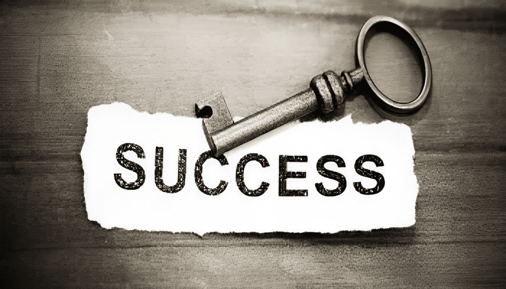 an antique metal key resting on a piece of torn white paper with the word "SUCCESS"