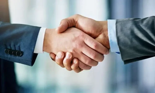 A close-up shot of two people in business suits shaking hands.