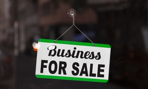 A white rectangular sign with a green border and the words "Business FOR SALE"
