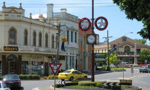 A view of a town intersection featuring historic buildings, including a prominent corner property occupied by a real estate agency.